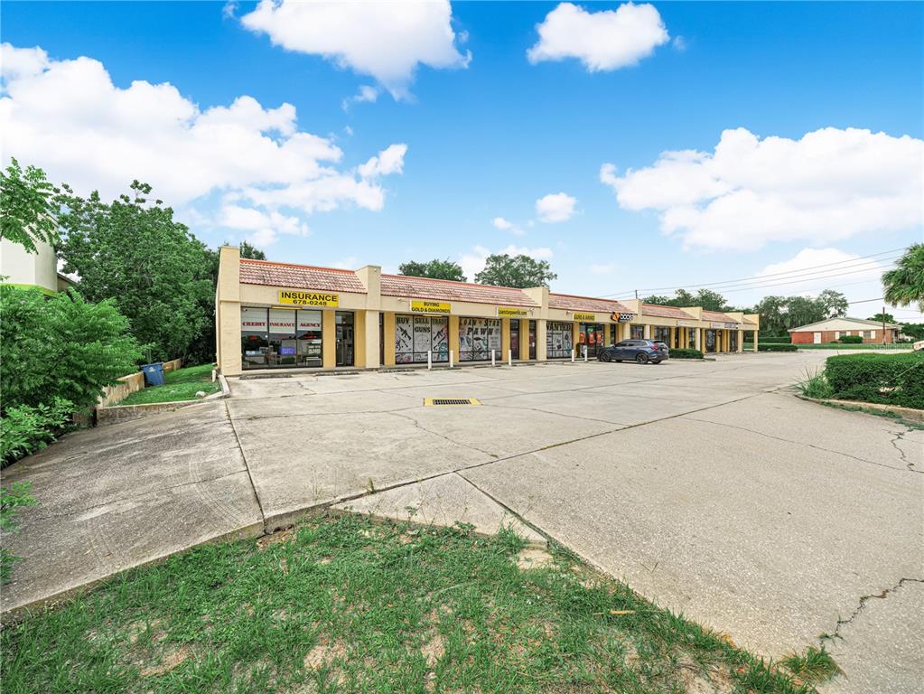 A single-story commercial strip mall with a concrete parking lot under a blue sky — 104 STATE ROAD 60 W, LAKE WALES, FL