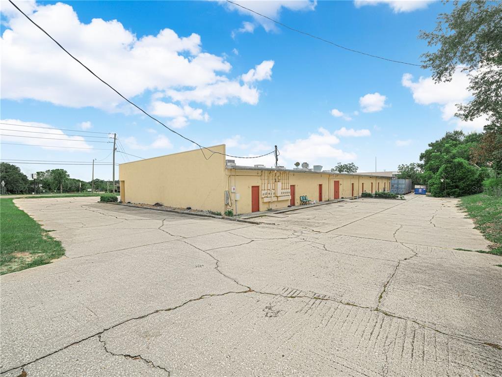 A low-rise commercial building with a large cracked concrete parking lot under a blue sky — 104 STATE ROAD 60 W, LAKE WALES, FL