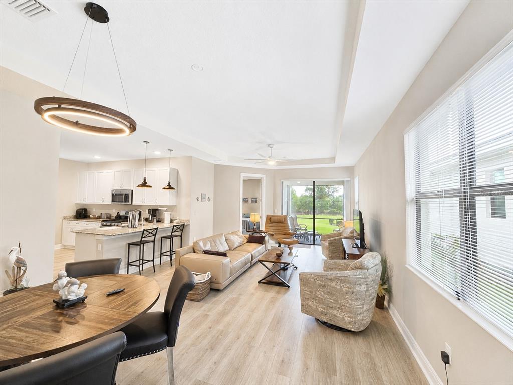 An open-concept living area features a kitchen with an island, dining space, and sliding doors — 5182 BARNETT CIRCLE, LAKEWOOD RANCH, FL