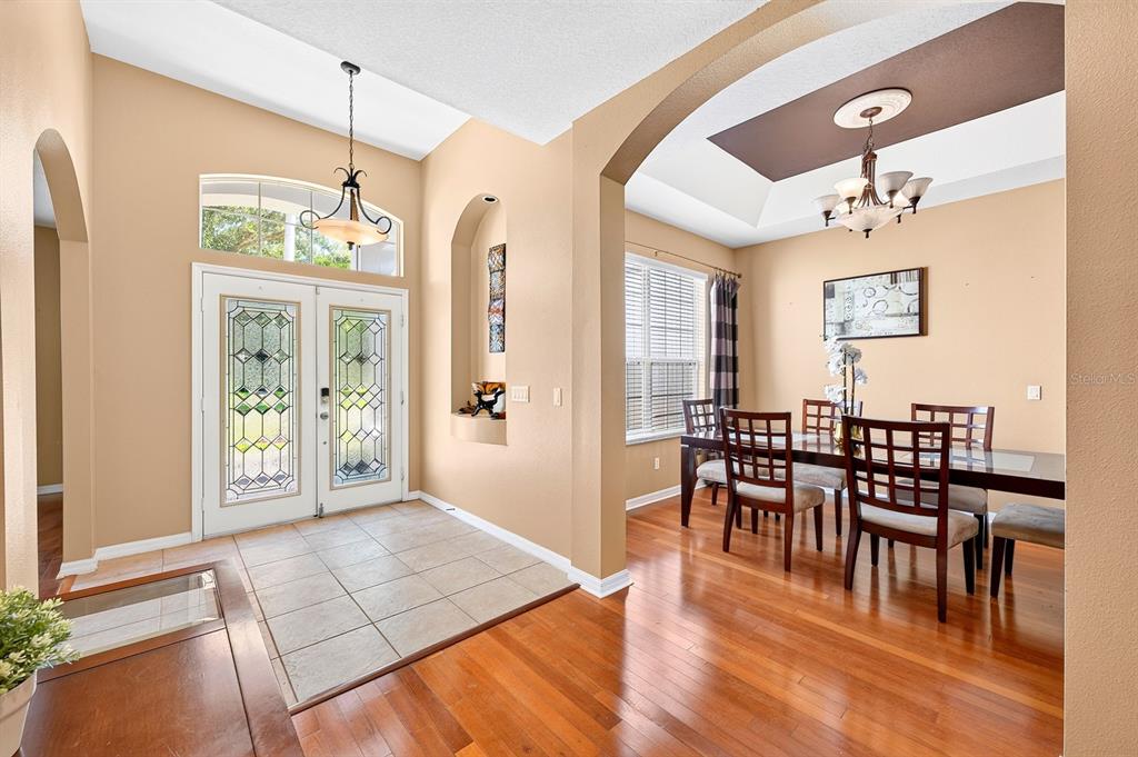 A foyer with tile flooring leads into a dining room featuring hardwood floors and chandeliers — 13537 KITTY FORK ROAD, ORLANDO, FL