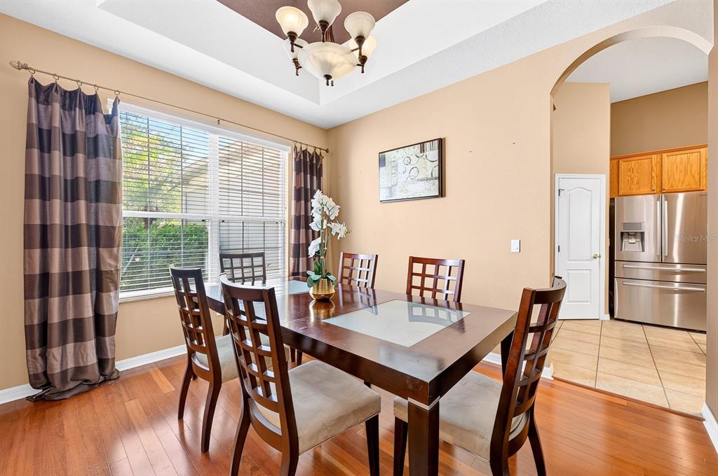 A dining room features a wooden table, six chairs, hardwood floors, and a tray ceiling — 13537 KITTY FORK ROAD, ORLANDO, FL