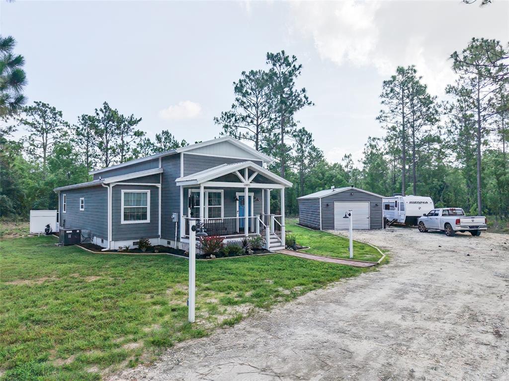 A gray house with a front porch stands next to a detached garage and driveway — 13971 SE 82ND LANE, DUNNELLON, FL