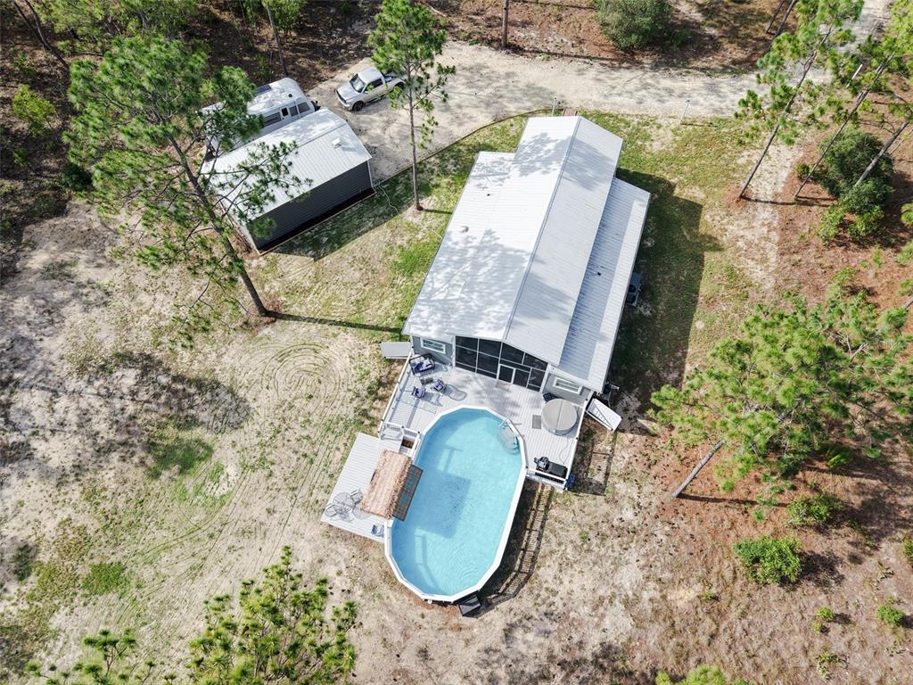 An aerial view shows a house with a pool, deck, and detached garage on land — 13971 SE 82ND LANE, DUNNELLON, FL