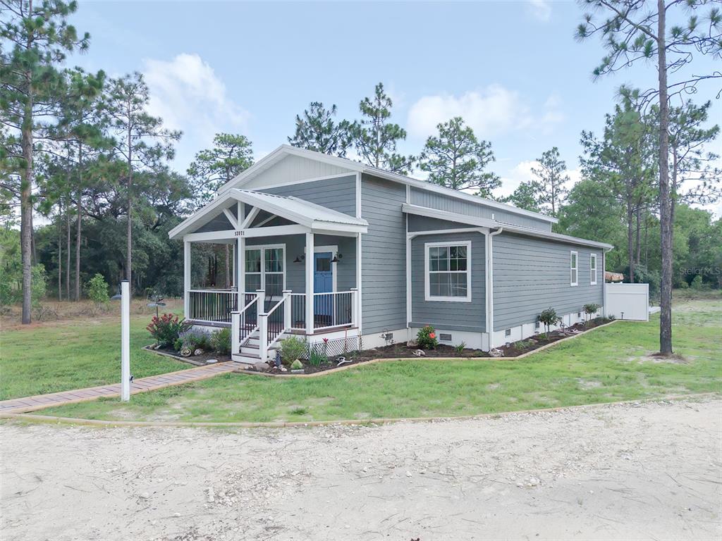 A single-story house with gray siding and a front porch sits on a grassy lot — 13971 SE 82ND LANE, DUNNELLON, FL