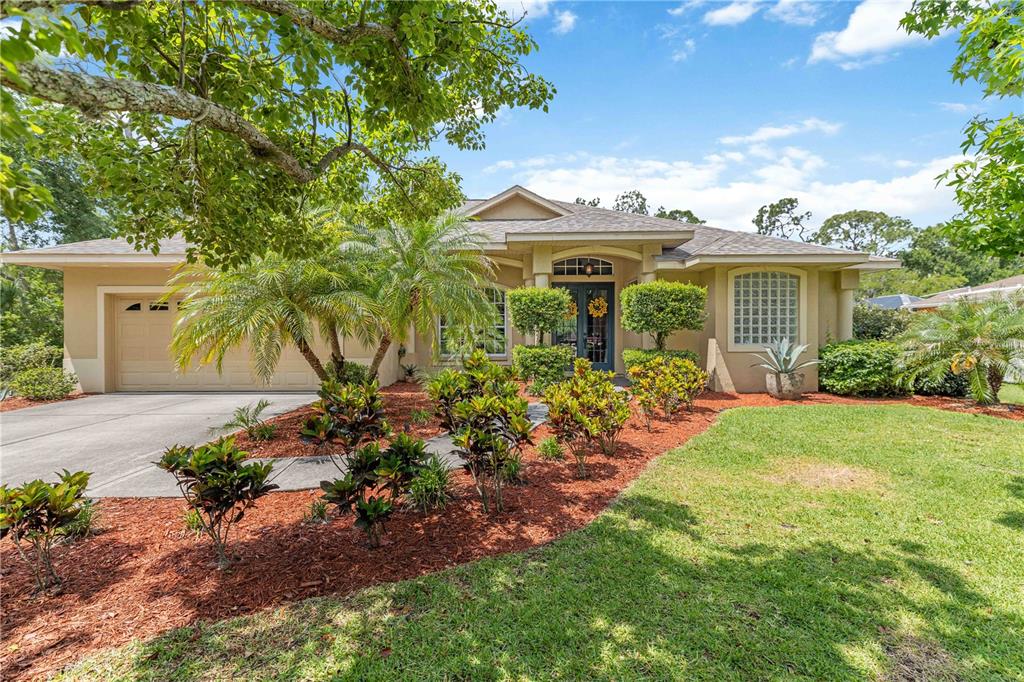 A single-story house with a beige stucco exterior, a two-car garage, and landscaped front yard — 13720 18TH PLACE E, BRADENTON, FL