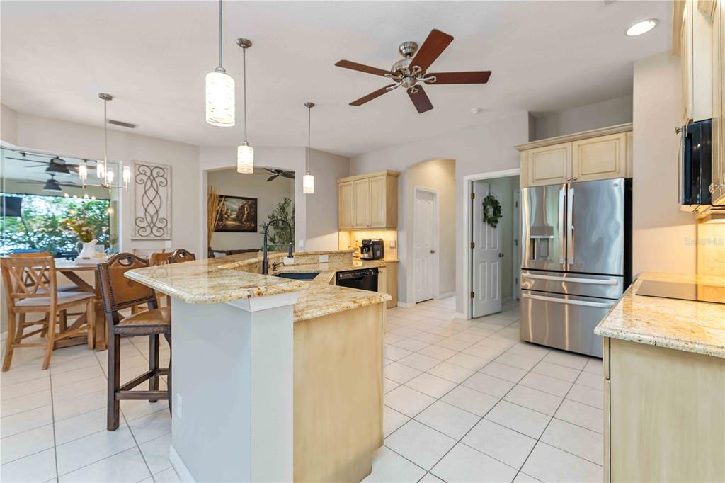 A kitchen with granite countertops, light wood cabinets, stainless steel appliances, and tile flooring — 13720 18TH PLACE E, BRADENTON, FL