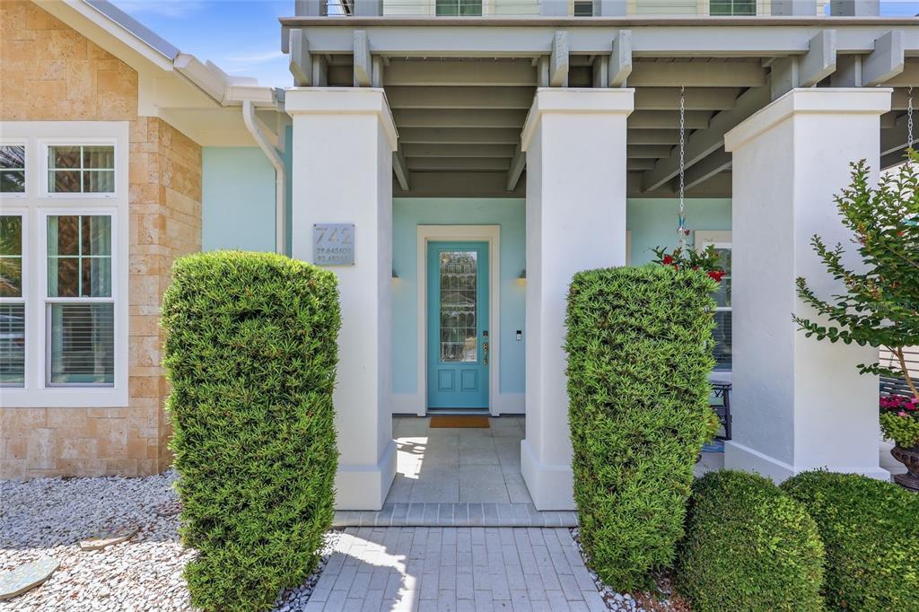 A light blue front door is framed by white columns and manicured hedges — 742 SW 132ND DRIVE, NEWBERRY, FL
