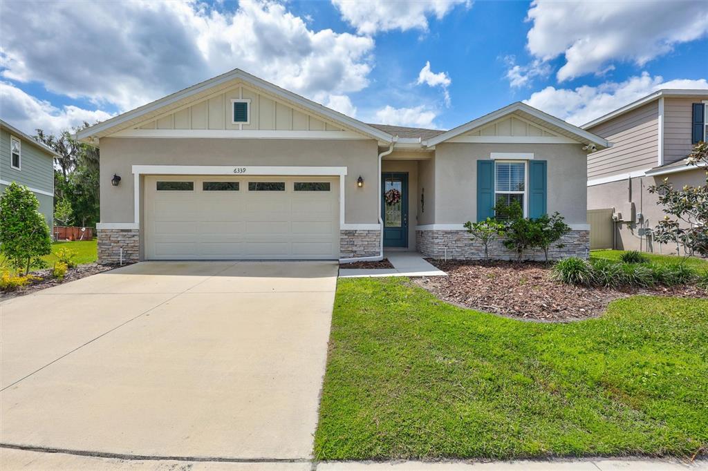 A single-story suburban house features a two-car garage, stone veneer accents, and a front lawn — 6339 DOLOSTONE DRIVE, LAKELAND, FL
