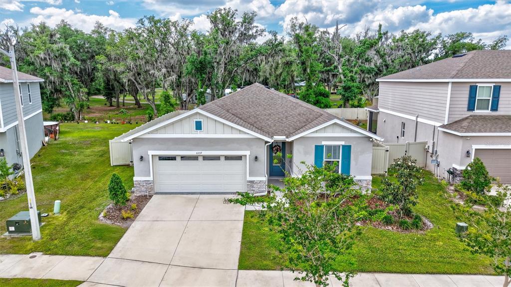 A single-story suburban house with a gray stucco exterior, a two-car garage, and blue shutters — 6339 DOLOSTONE DRIVE, LAKELAND, FL