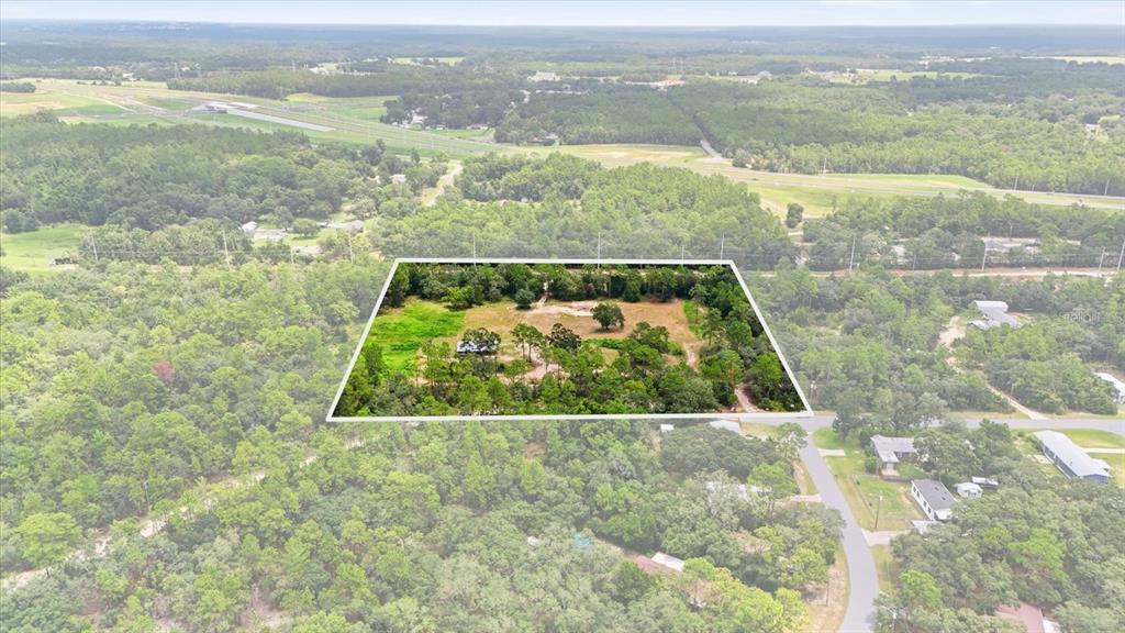 An aerial view shows a rectangular plot of land with trees and a small structure — 209 S SPICE WOOD TERRACE, LECANTO, FL