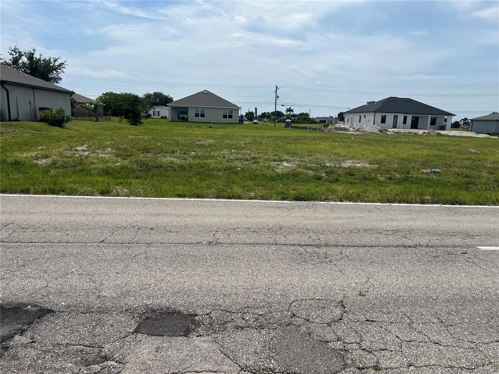 A grassy, vacant residential lot under a blue sky with scattered clouds — 2612 SANTA BARBARA BOULEVARD N, CAPE CORAL, FL