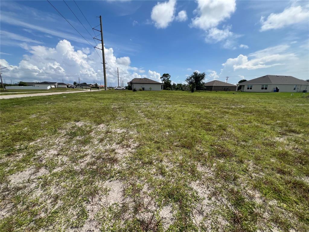 A vacant, grassy residential lot under a blue sky with scattered clouds — 2612 SANTA BARBARA BOULEVARD N, CAPE CORAL, FL