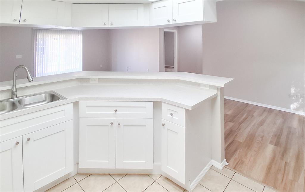 A kitchen with white cabinets, a peninsula countertop, and a stainless steel sink — 4311 THONOTOSASSA AVENUE, TAMPA, FL