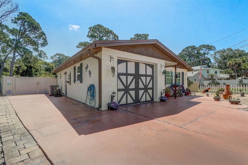 A detached garage with a tan exterior, dark trim, and a large concrete driveway — 298 POINCIANA AVENUE, PORT ORANGE, FL