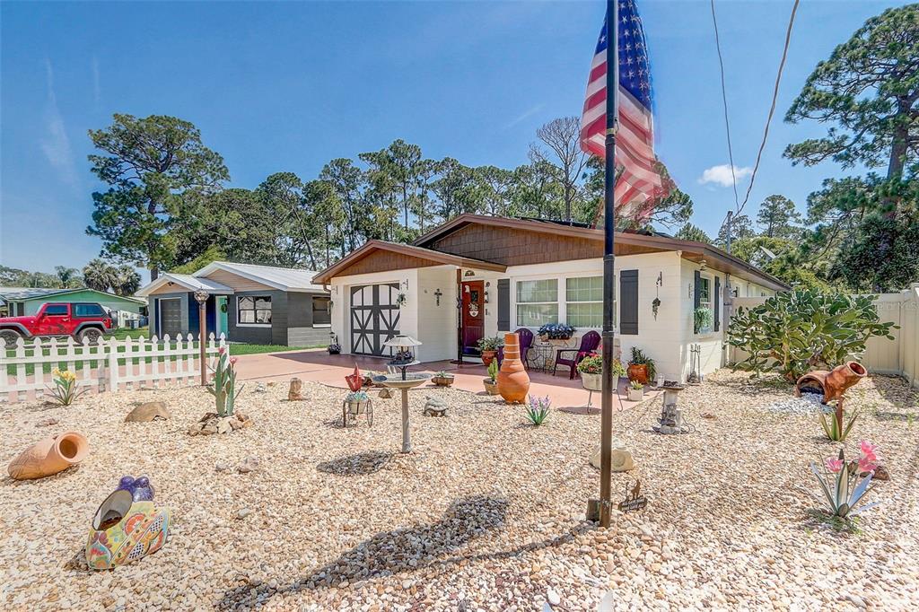 A single-story house with a gravel yard, a white picket fence, and an American flag — 298 POINCIANA AVENUE, PORT ORANGE, FL
