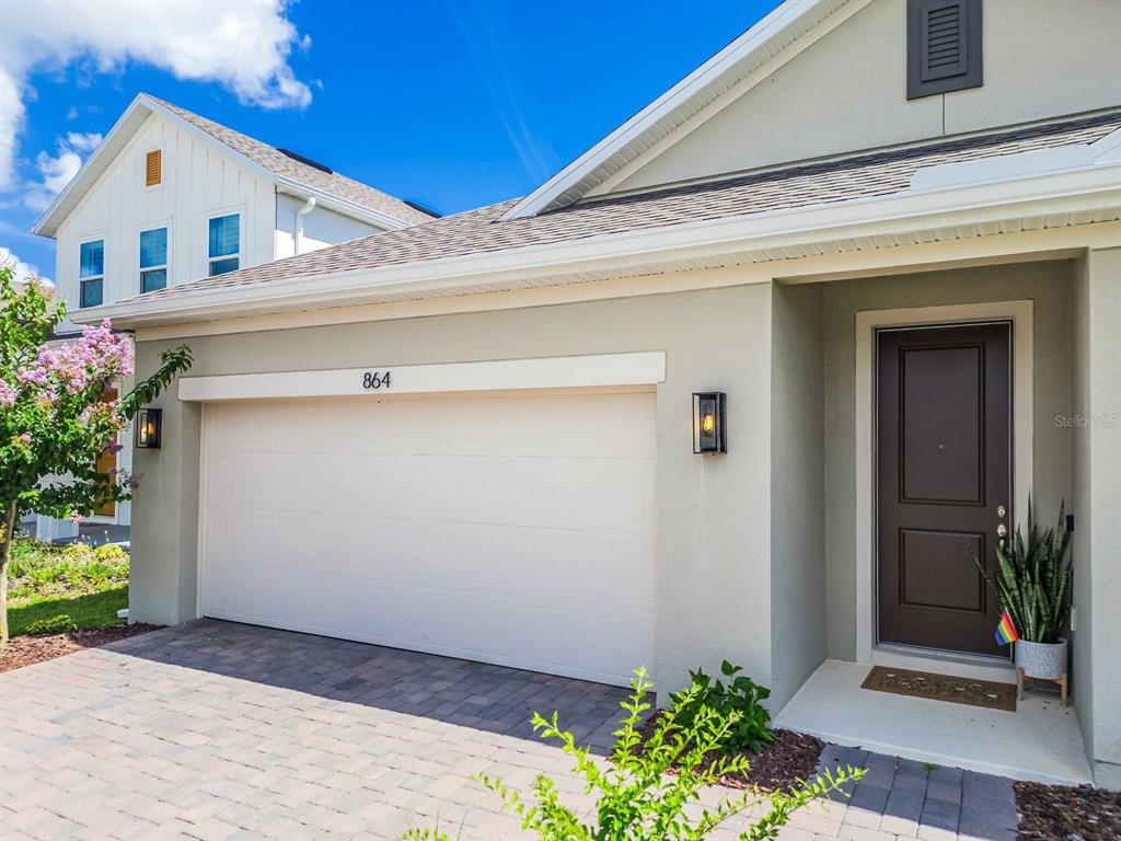 The exterior of a house features a two-car garage, a brown front door, and landscaping — 864 VINEYARD RIDGE ROAD, MINNEOLA, FL