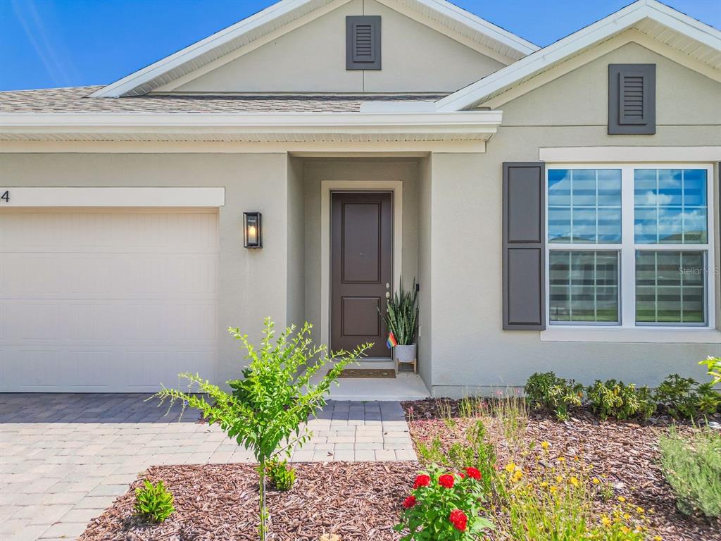 A single-story house exterior features a beige facade, a brown front door, and a garage — 864 VINEYARD RIDGE ROAD, MINNEOLA, FL