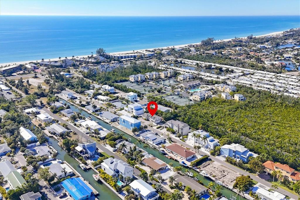 An aerial view shows a coastal neighborhood with houses situated along narrow canals near the ocean — 651 JUNGLE QUEEN WAY, LONGBOAT KEY, FL