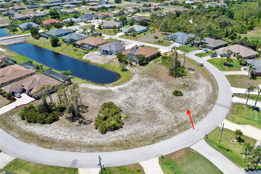 An aerial view shows a vacant, sandy residential lot situated along a curved street — 15 MEDALIST WAY, ROTONDA WEST, FL