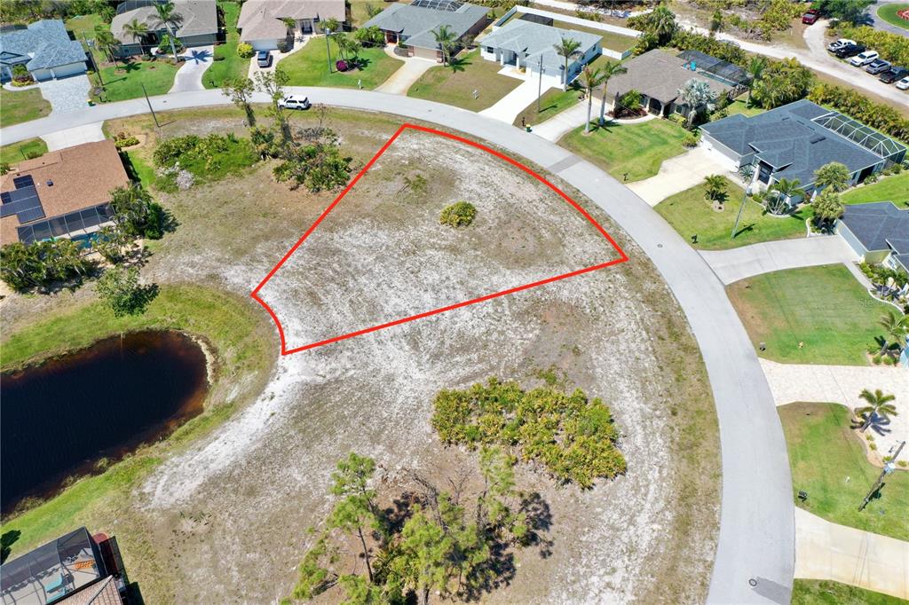 An aerial view shows a vacant, triangular residential lot outlined in red next to a pond — 15 MEDALIST WAY, ROTONDA WEST, FL