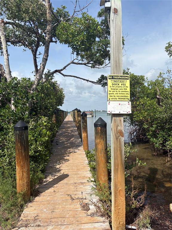 A wooden dock extends into the water, flanked by mangroves and a no trespassing sign — 8990 SEAGRAPE LANE, PLACIDA, FL