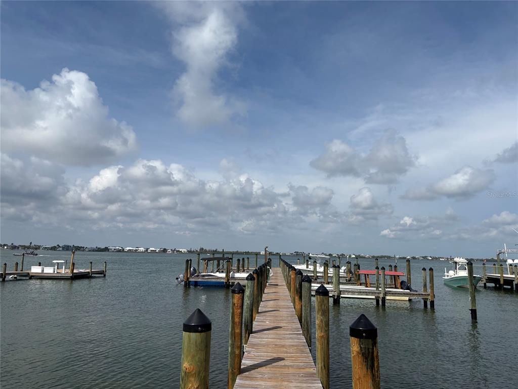 A wooden dock extends into a bay with several boats moored at nearby slips — 8990 SEAGRAPE LANE, PLACIDA, FL