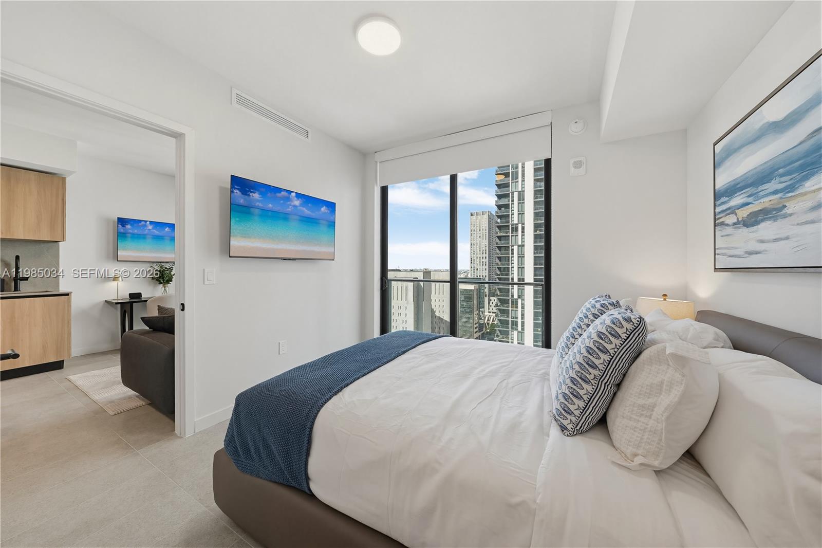 A modern bedroom features a bed, wall-mounted television, and a sliding glass door with city views — 121 NE 5th St # 2706, Miami FL 33132, MIAMI, FL