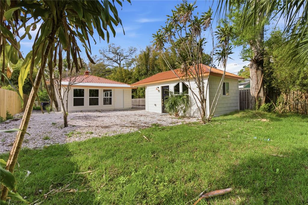 Two small white detached buildings with orange metal roofs sit in a grassy backyard — 5211 25TH AVENUE S, GULFPORT, FL