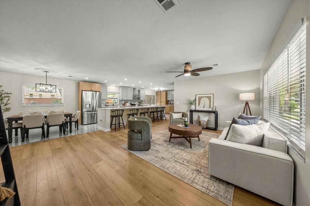 An open-concept living and dining area features light wood flooring, a kitchen island, and furniture — 912 NE 17TH COURT, OCALA, FL