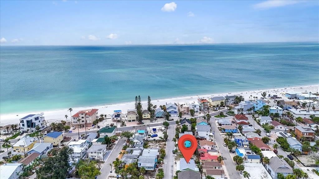 An aerial view shows a beachside neighborhood with a red location pin over a house — 130 86TH TERRACE, TREASURE ISLAND, FL
