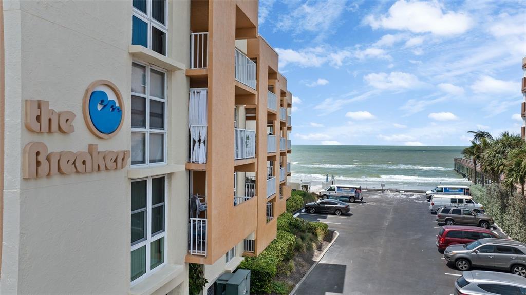 An exterior view of a multi-story beachside apartment building with a parking lot and ocean — 16308 GULF BOULEVARD UNIT 209, REDINGTON BEACH, FL