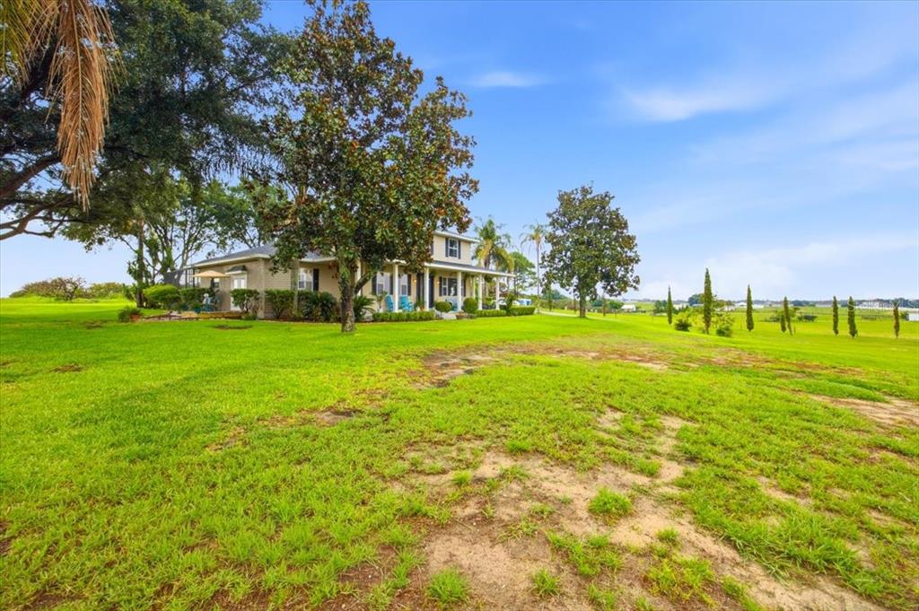 A two-story house with a front porch sits on a large, grassy rural lot — 915 N CROOKED LAKE DRIVE, BABSON PARK, FL