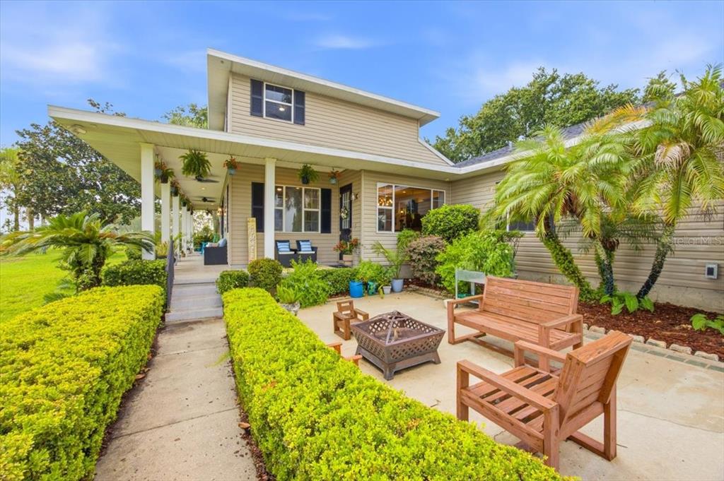 A beige two-story house features a covered porch, a concrete patio, and wooden outdoor furniture — 915 N CROOKED LAKE DRIVE, BABSON PARK, FL