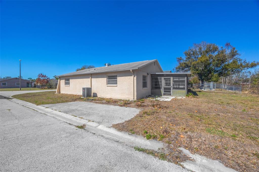 A single-story tan house with a screened-in porch and a concrete driveway — 12622 TIMBERWOOD COURT, HUDSON, FL