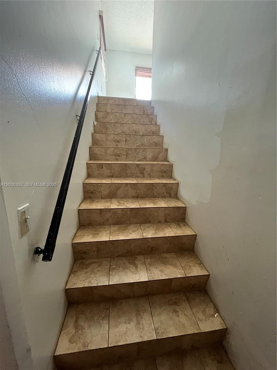 A staircase with tan tiled steps and a black metal handrail leads upward — 334 E 21st St # 5, Hialeah FL 33010, HIALEAH, FL