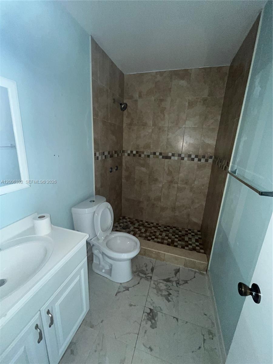This bathroom features a tiled walk-in shower, a white vanity, and a toilet — 334 E 21st St # 5, Hialeah FL 33010, HIALEAH, FL