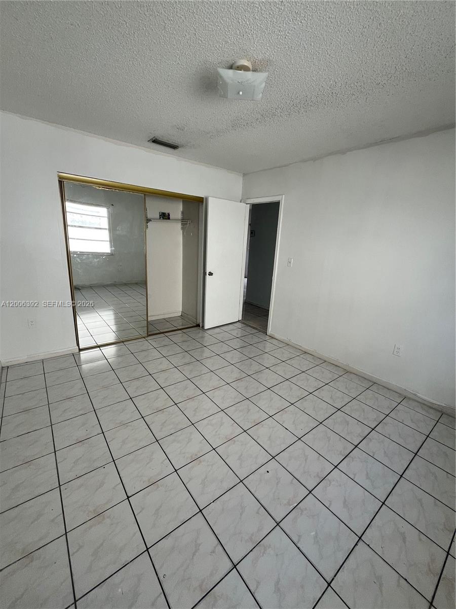 A bedroom features white walls, a tiled floor, a mirrored closet, and a ceiling light — 334 E 21st St # 5, Hialeah FL 33010, HIALEAH, FL