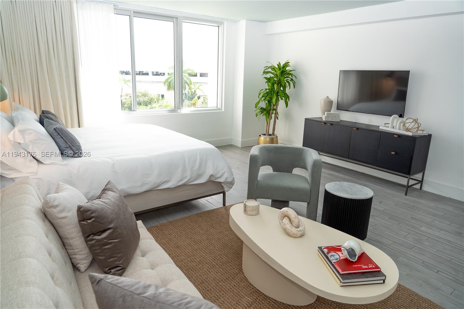 A modern bedroom features a bed, seating area, television console, and large windows — 1100 West Ave # 415, Miami Beach FL 33139, MIAMI BEACH, FL