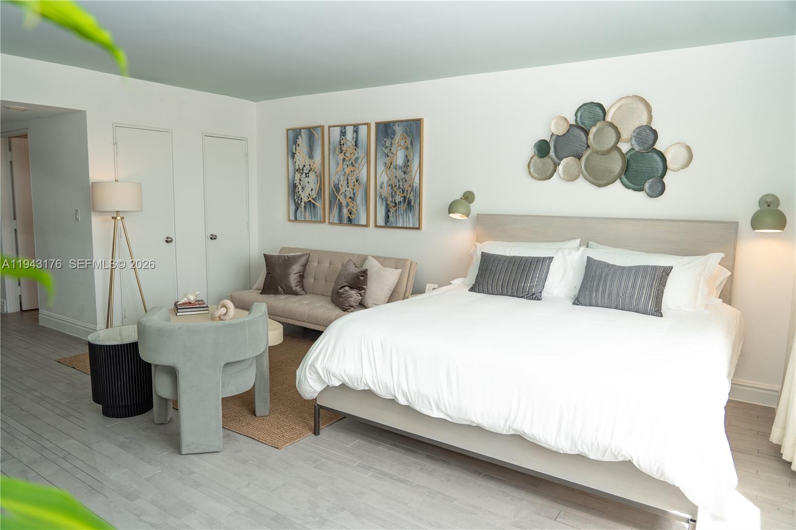 A bedroom features a bed, a small sofa, a chair, and wall-mounted art — 1100 West Ave # 415, Miami Beach FL 33139, MIAMI BEACH, FL
