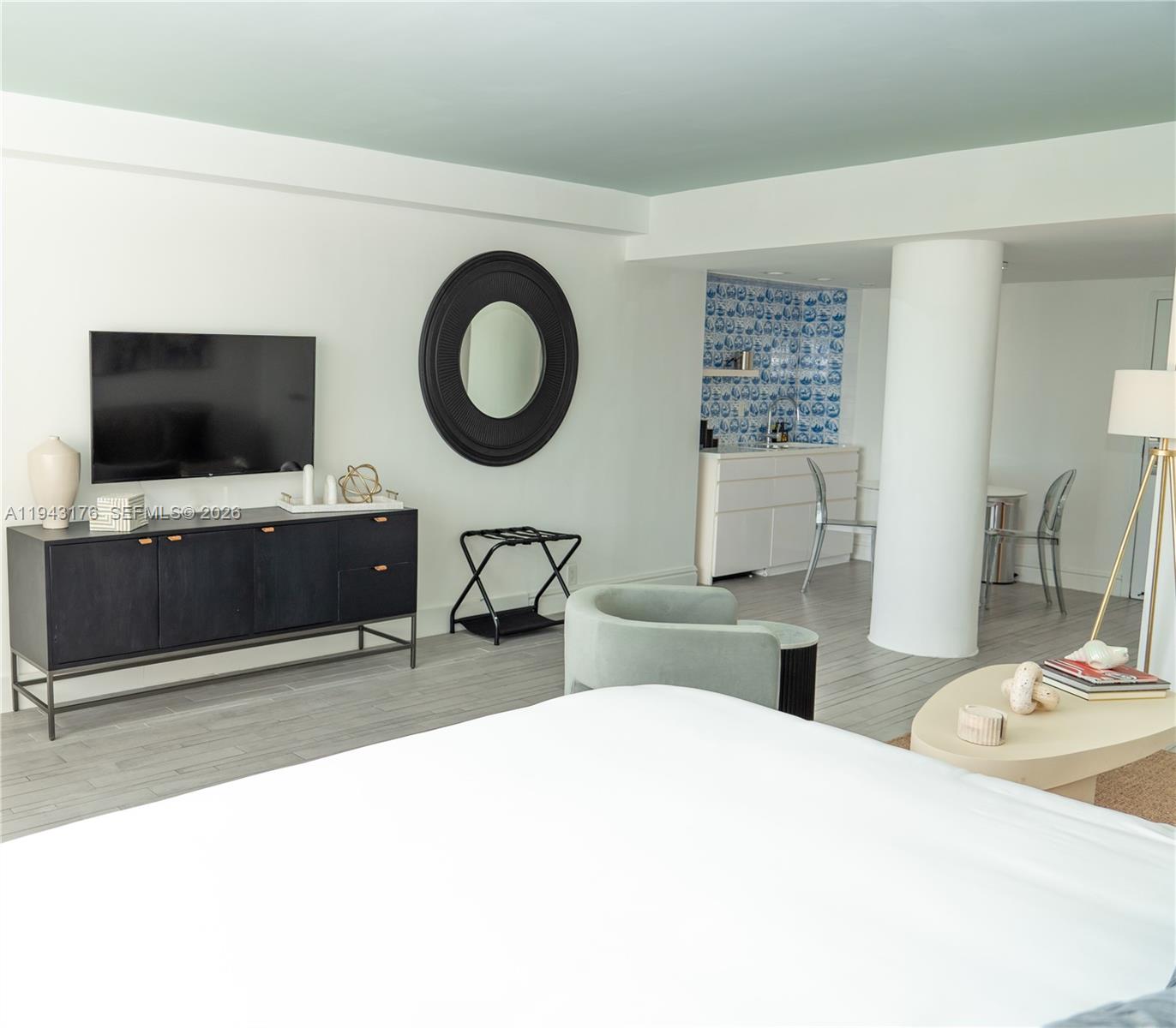 A bedroom features a television, a black console, a round mirror, and a small kitchenette — 1100 West Ave # 415, Miami Beach FL 33139, MIAMI BEACH, FL