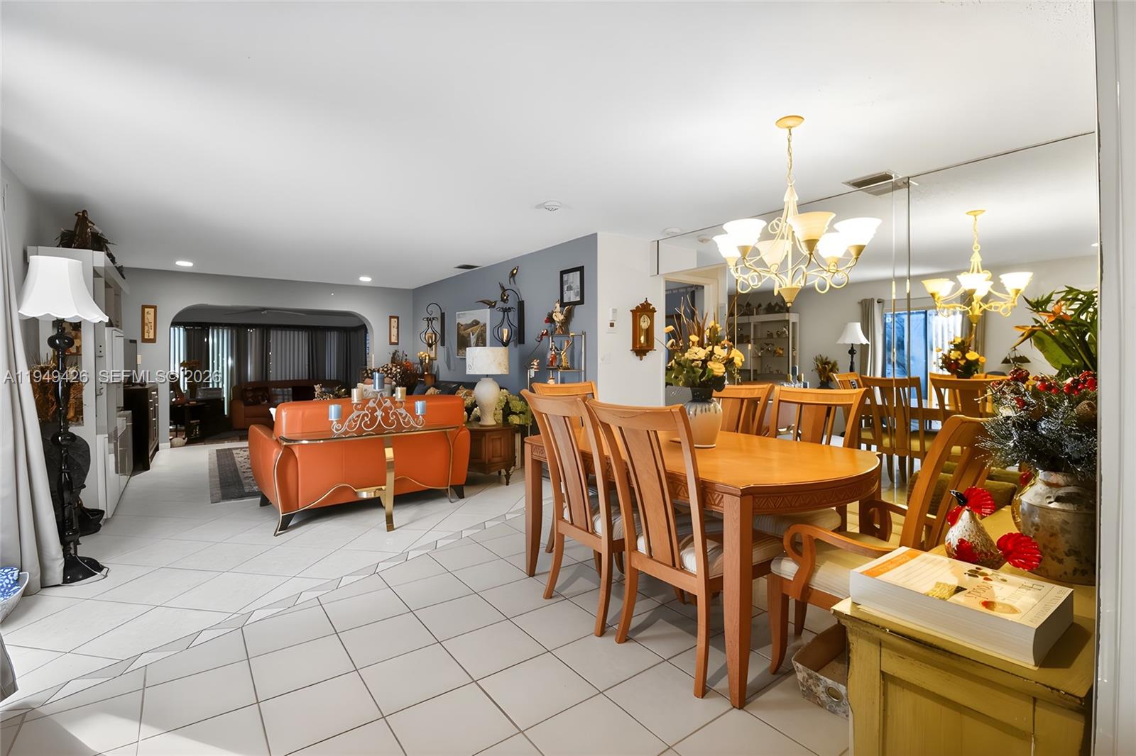 A dining room with a wooden table and chairs sits adjacent to a living area — 2214 Seagrape Cir, Coconut Creek FL 33066, COCONUT CREEK, FL