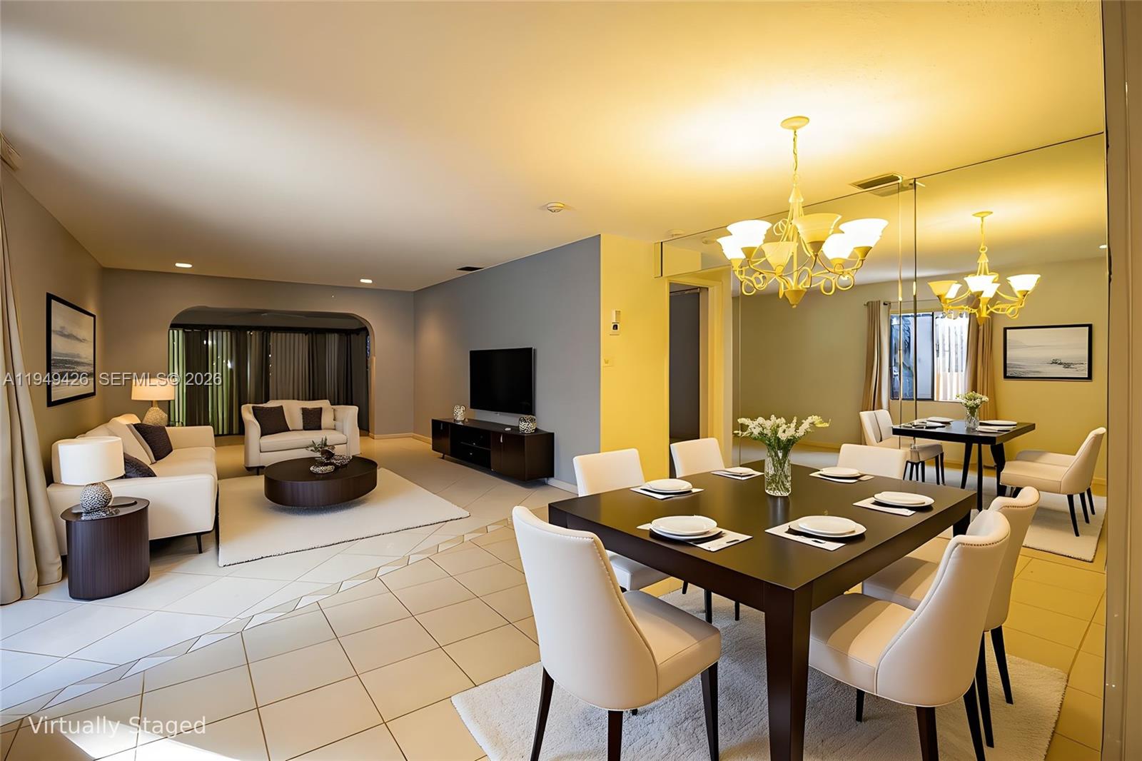 This virtually staged living and dining area features tile flooring, a chandelier, and mirrored walls — 2214 Seagrape Cir, Coconut Creek FL 33066, COCONUT CREEK, FL