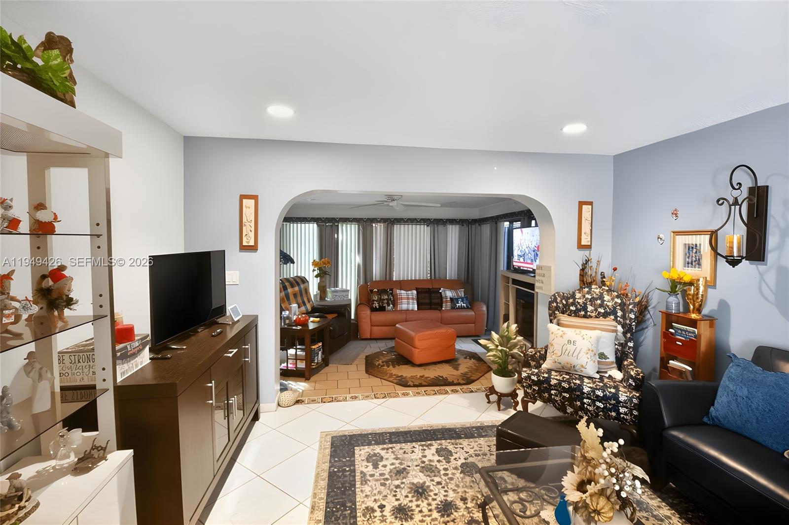 A living room with light blue walls, tile flooring, and an arched opening to a den — 2214 Seagrape Cir, Coconut Creek FL 33066, COCONUT CREEK, FL
