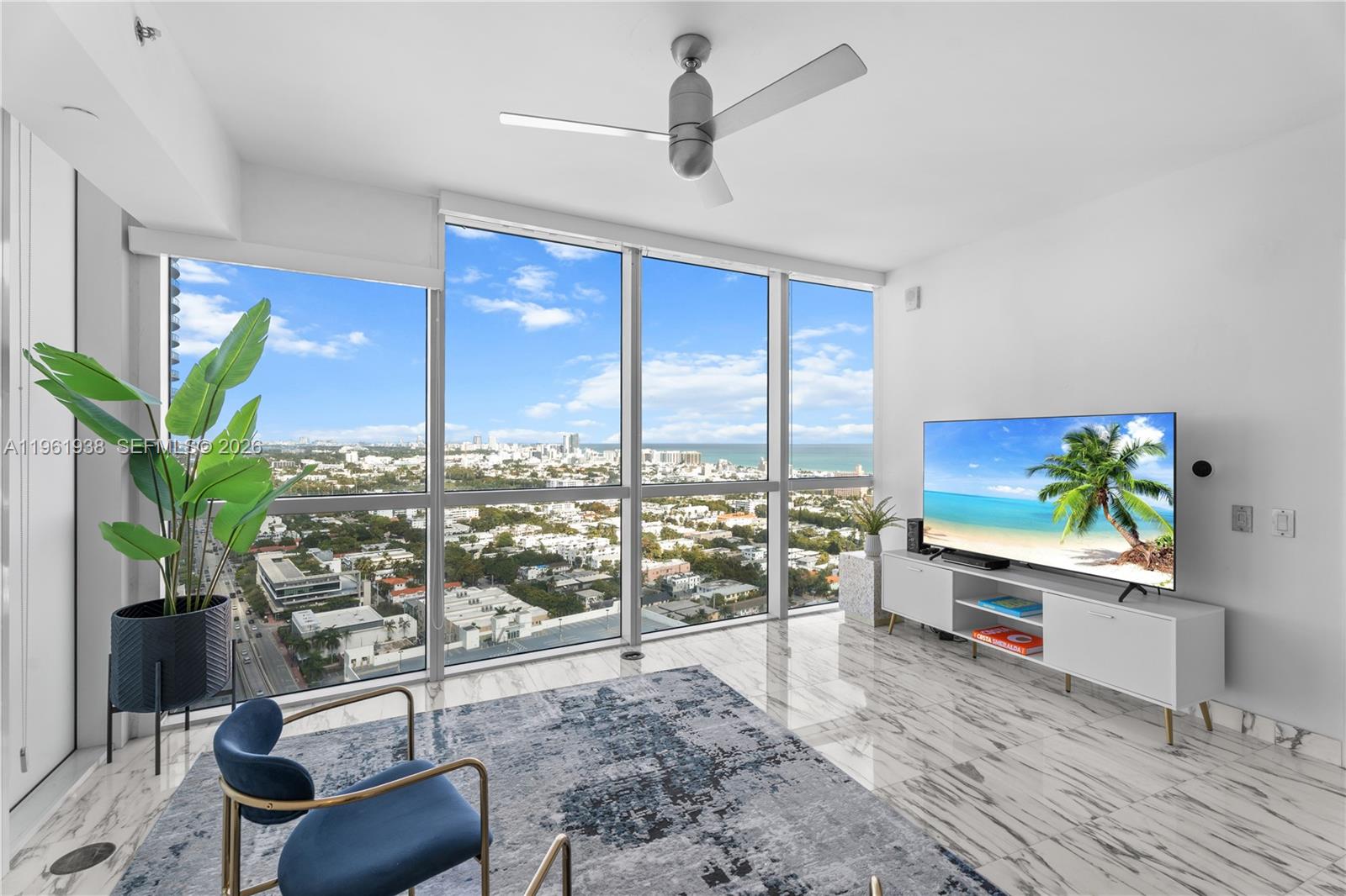 A living room features floor-to-ceiling windows, marble flooring, a blue rug, and city views — 450 Alton Rd # 3008, Miami Beach FL 33139, MIAMI BEACH, FL