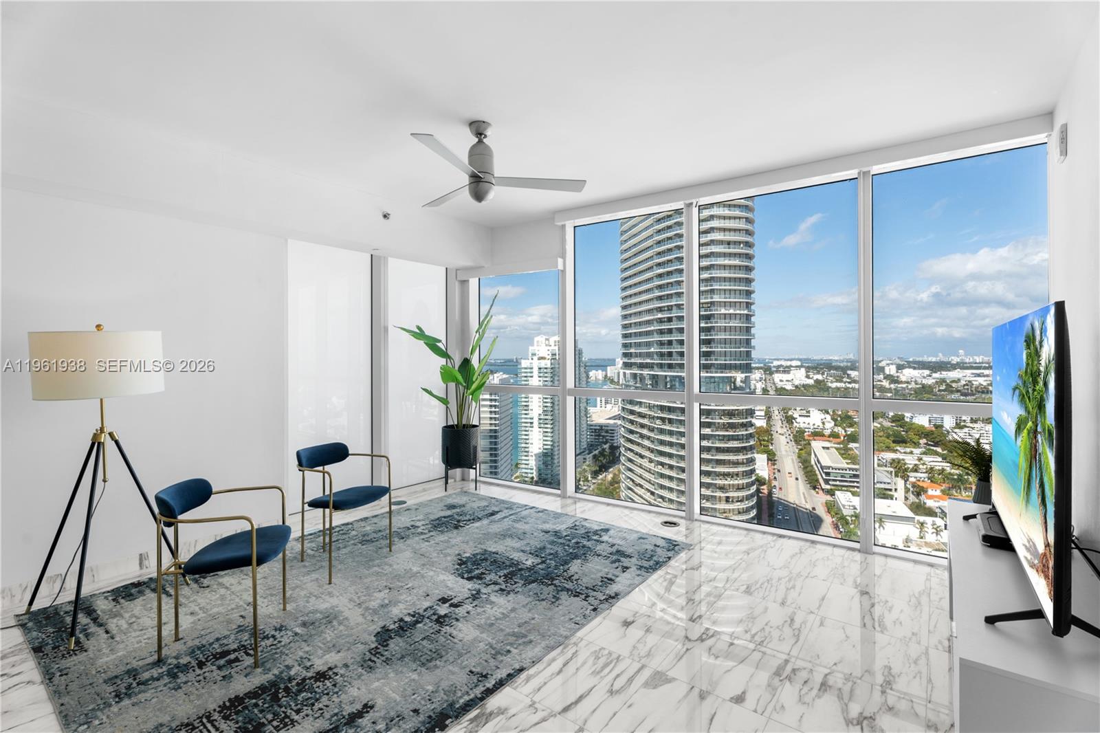 A modern living room features floor-to-ceiling windows, marble floors, and a view of city skyscrapers — 450 Alton Rd # 3008, Miami Beach FL 33139, MIAMI BEACH, FL