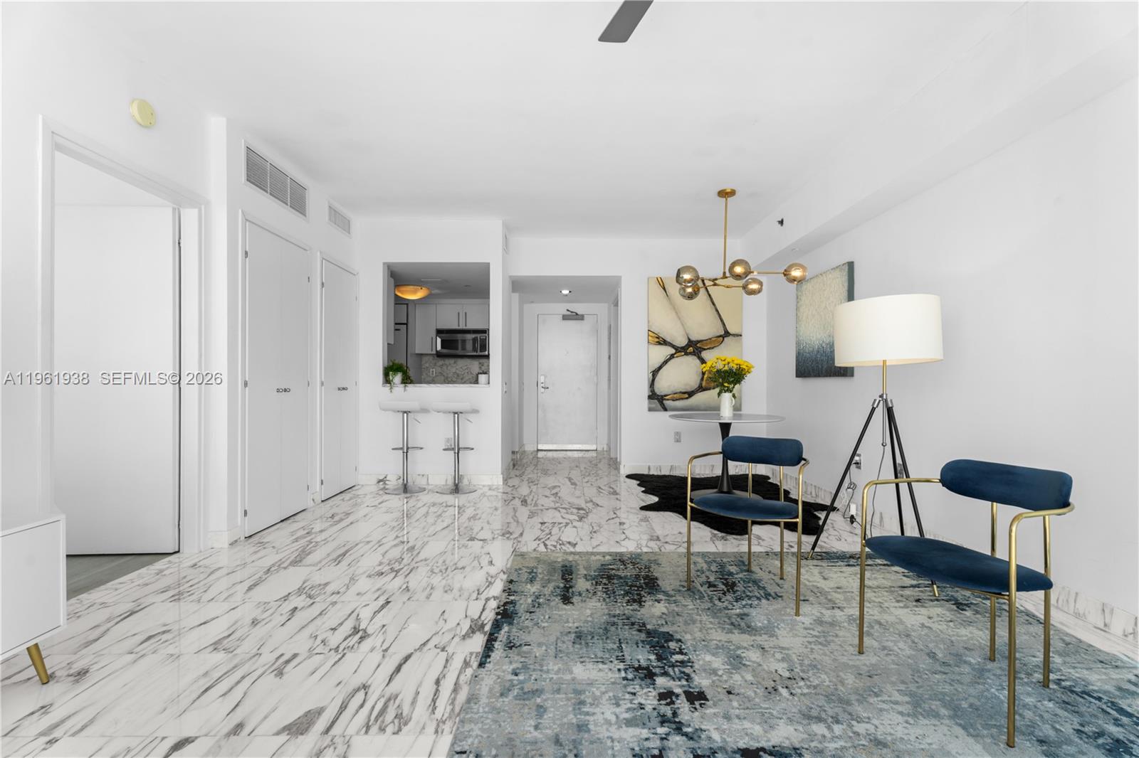 A bright dining and living area features marble floors, blue velvet chairs, and a chandelier — 450 Alton Rd # 3008, Miami Beach FL 33139, MIAMI BEACH, FL