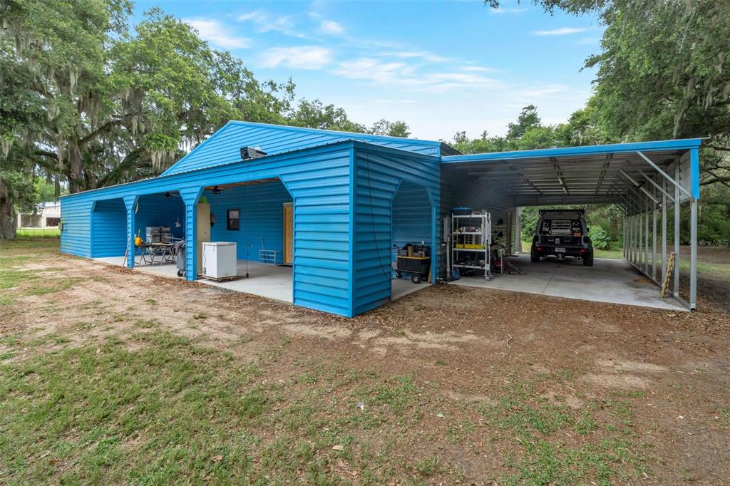 A blue metal building with an attached open-sided carport and a concrete patio area — 2102 OLD POLK CITY ROAD, LAKELAND, FL