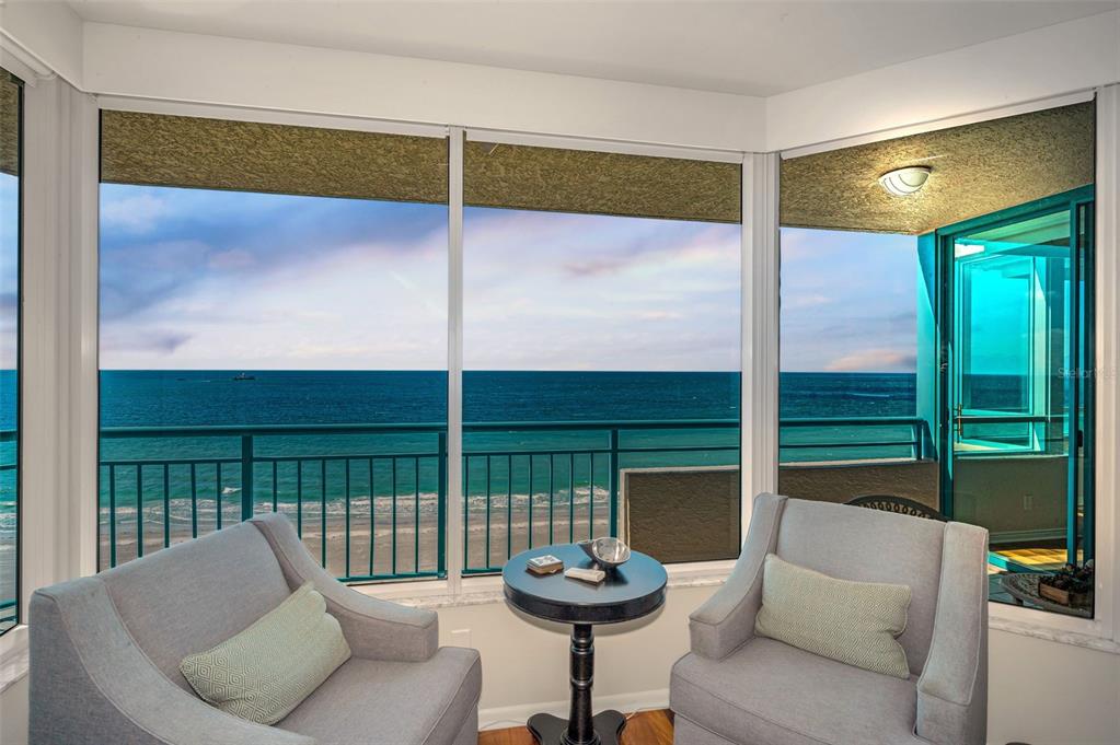 Two armchairs and a small table sit before large windows overlooking the ocean — 1520 GULF BOULEVARD UNIT 1101, CLEARWATER BEACH, FL