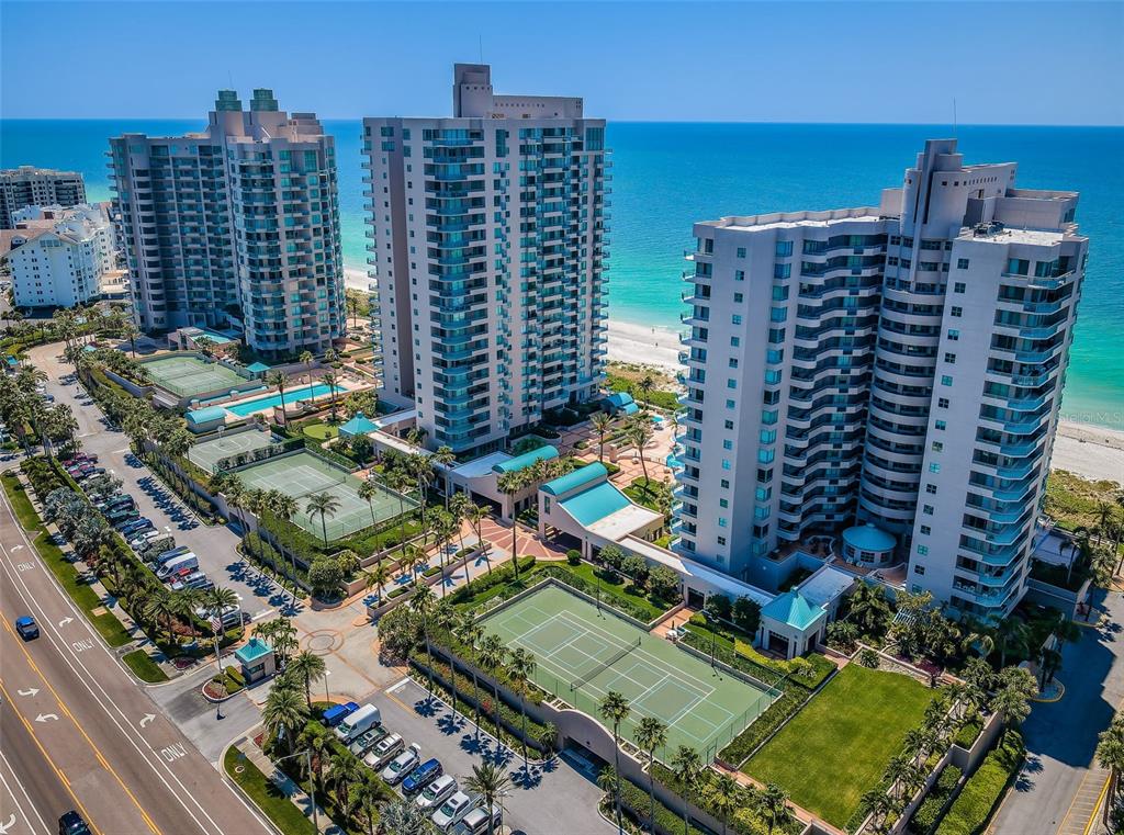 An aerial view of three high-rise residential buildings with tennis courts and a beach nearby — 1520 GULF BOULEVARD UNIT 1101, CLEARWATER BEACH, FL