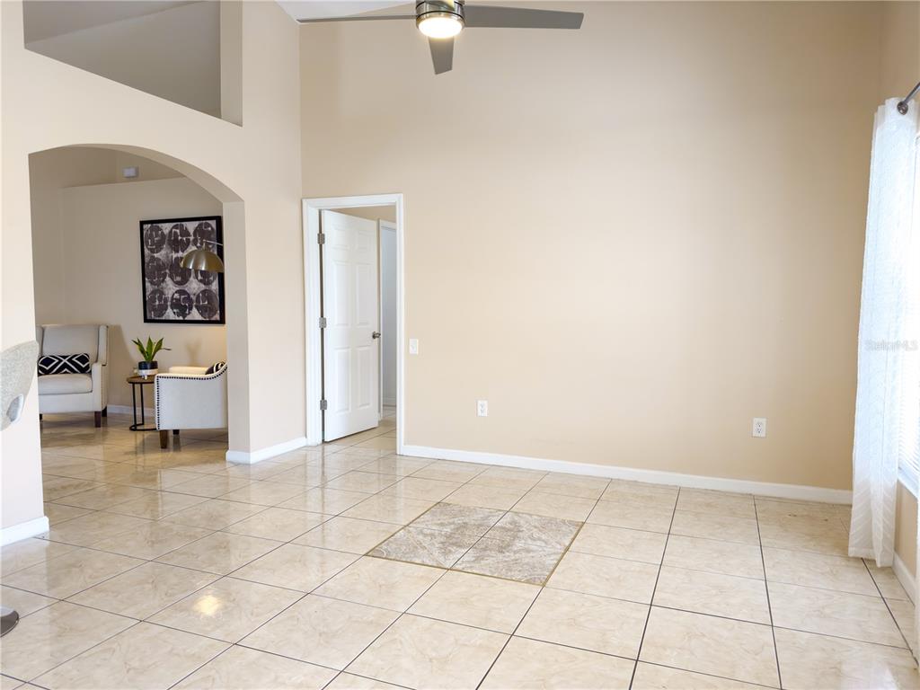 A spacious room with beige tile flooring, high ceilings, and a ceiling fan — 3245 WHOOPING CRANE RUN, KISSIMMEE, FL